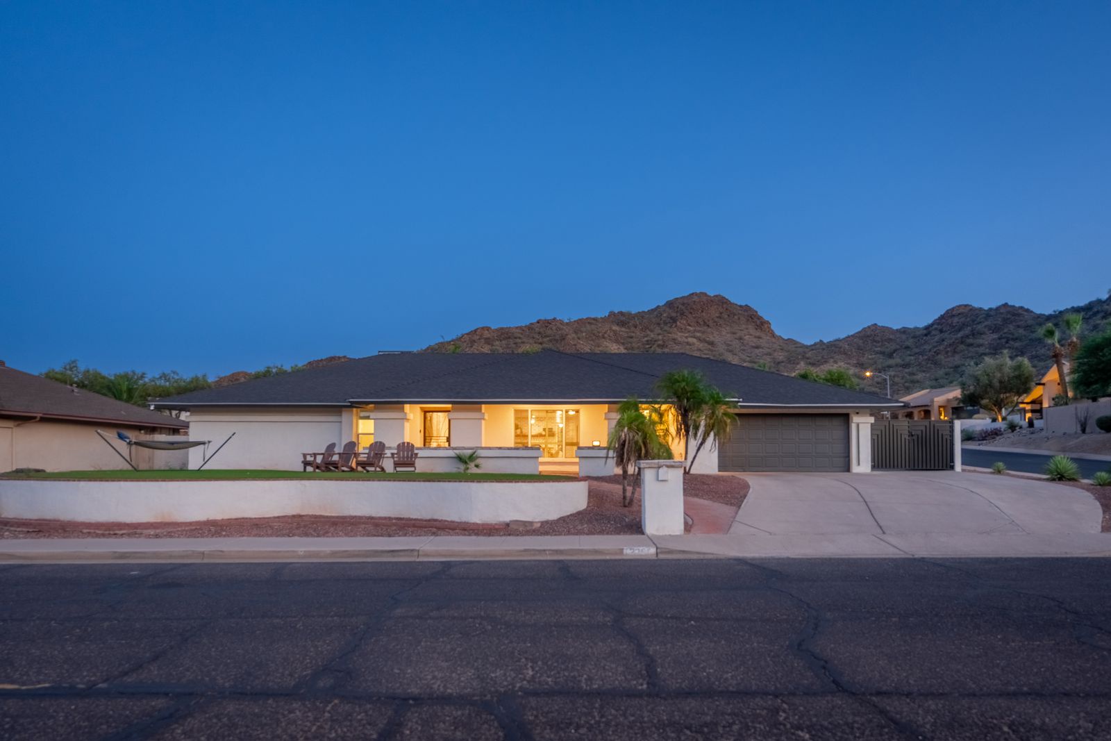 Modern desert retreat set against striking mountain backdrop, captured during twilight hour with warm lighting and contemporary architecture.