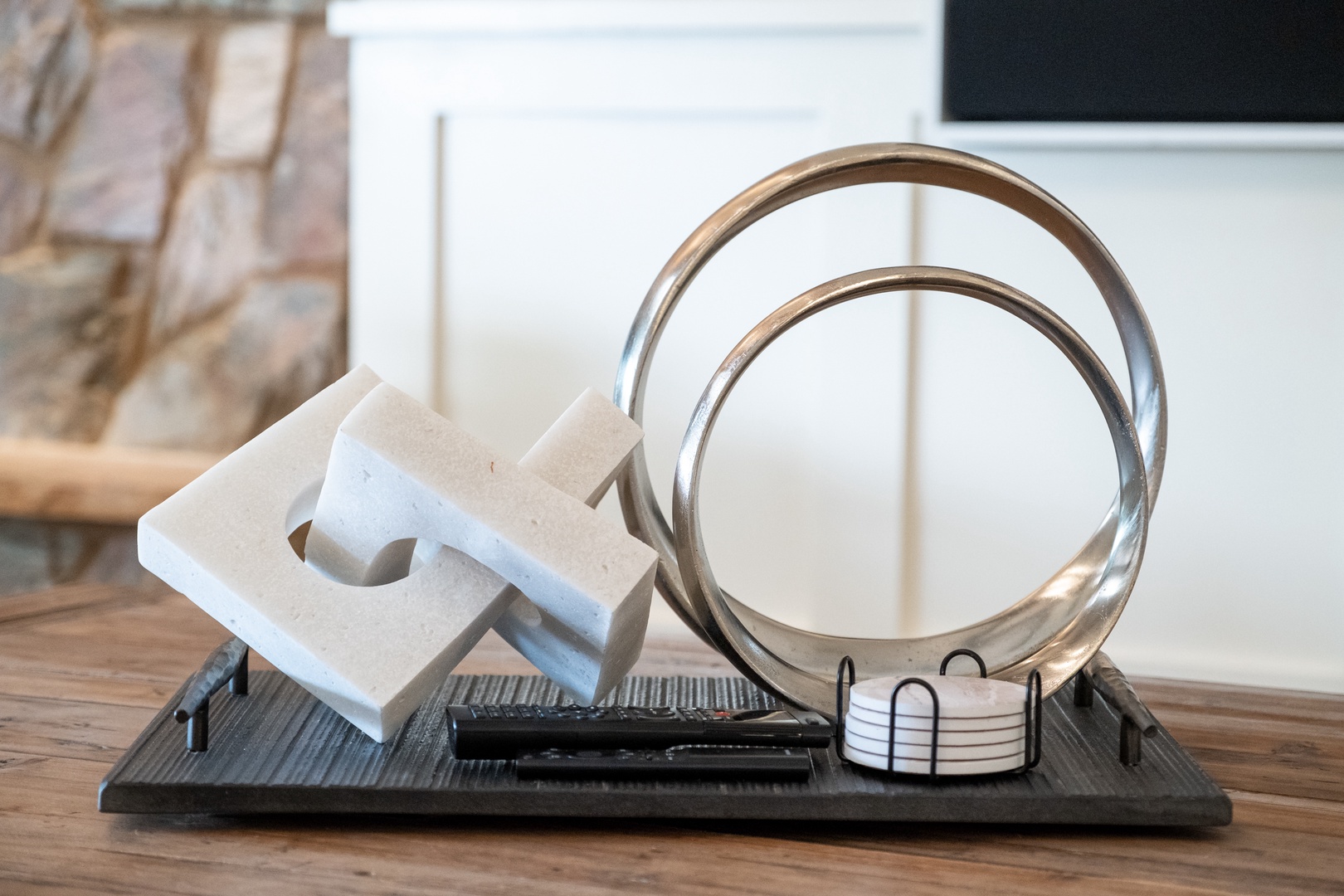 Modern sculptural pieces and coasters arranged on a sleek tray bring an artistic, curated touch to your living space.