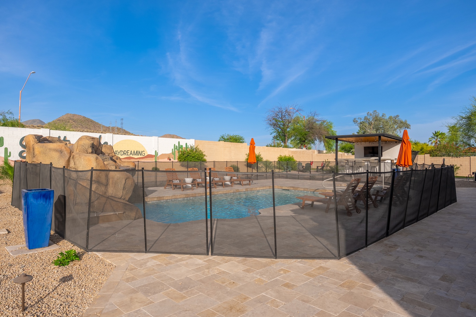 A secure pool area featuring a desert-inspired waterslide nestled in the sunny Arizona landscape, perfect for family fun under clear blue skies.