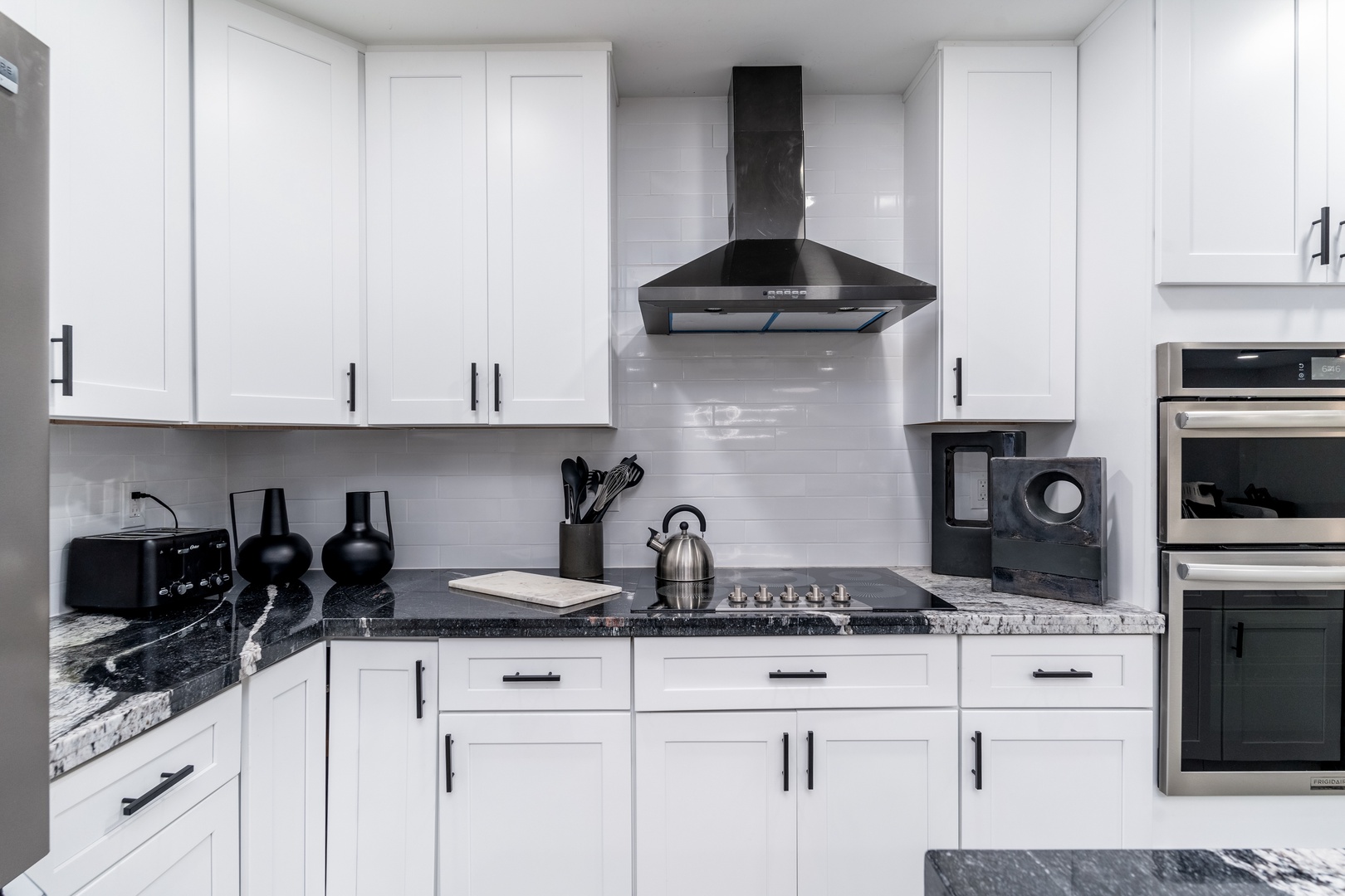 Your sleek, fully-equipped kitchen features elegant white cabinetry, granite counters, and modern stainless appliances—ready for your culinary adventures.