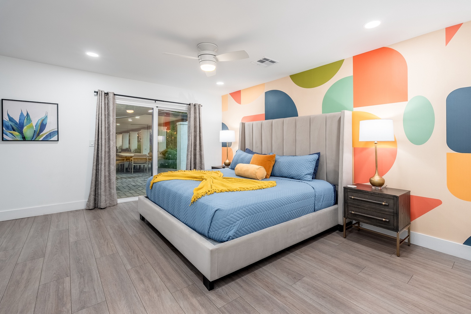 Drift off to sleep in your vibrant bedroom, where a plush bed awaits beneath a playful accent wall of colors. The patio access offers your private escape for morning coffee or evening relaxation.
