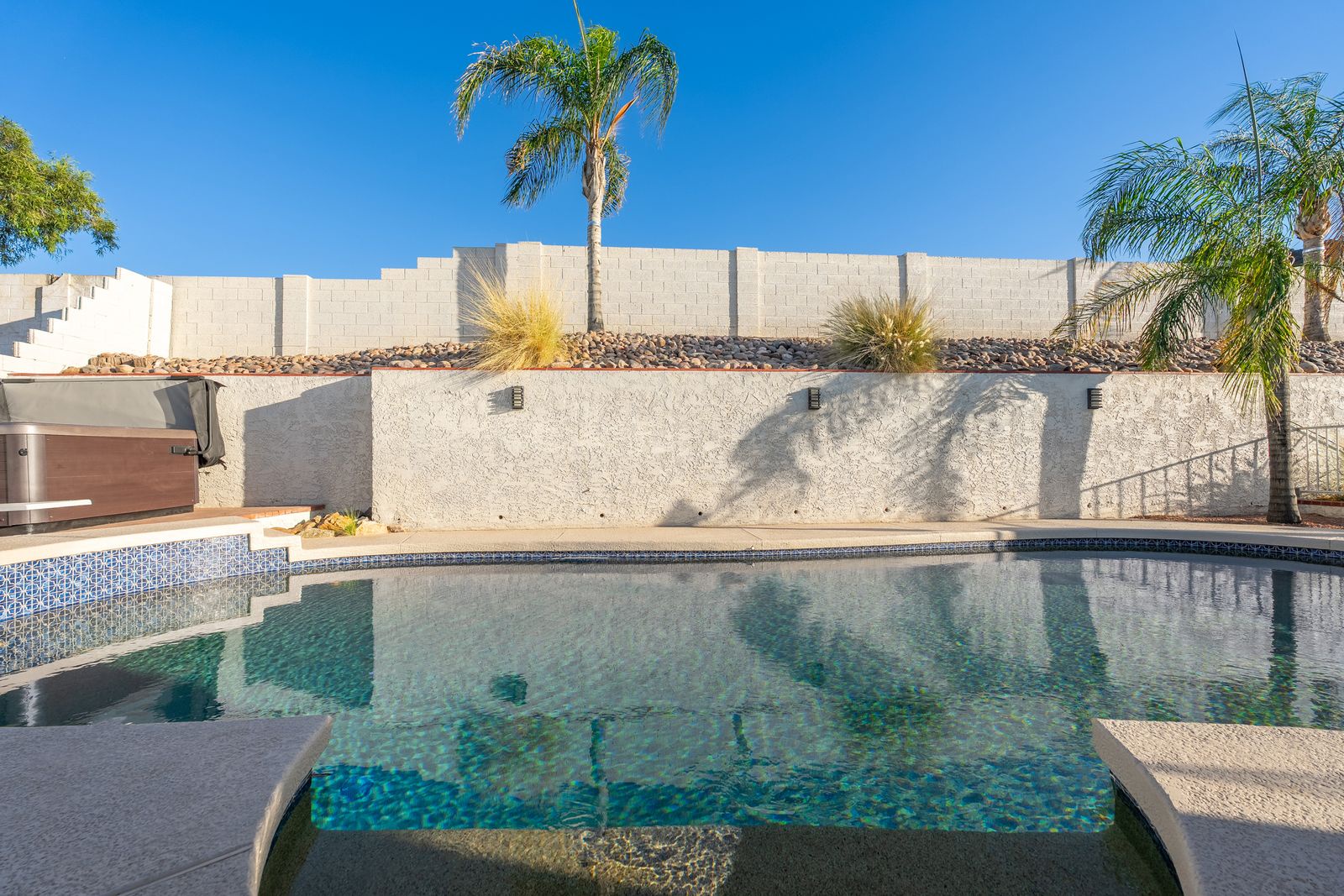 Your private oasis awaits under sunny skies—sparkling pool, swaying palms, and desert beauty creating the perfect backdrop for relaxation and fun.