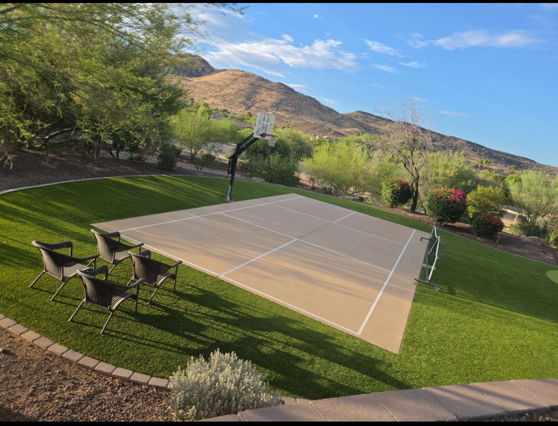 A private backyard oasis set against rugged mountain views, featuring a full-size sport court, basketball hoop, and landscaped grounds perfect for outdoor recreation and relaxation.