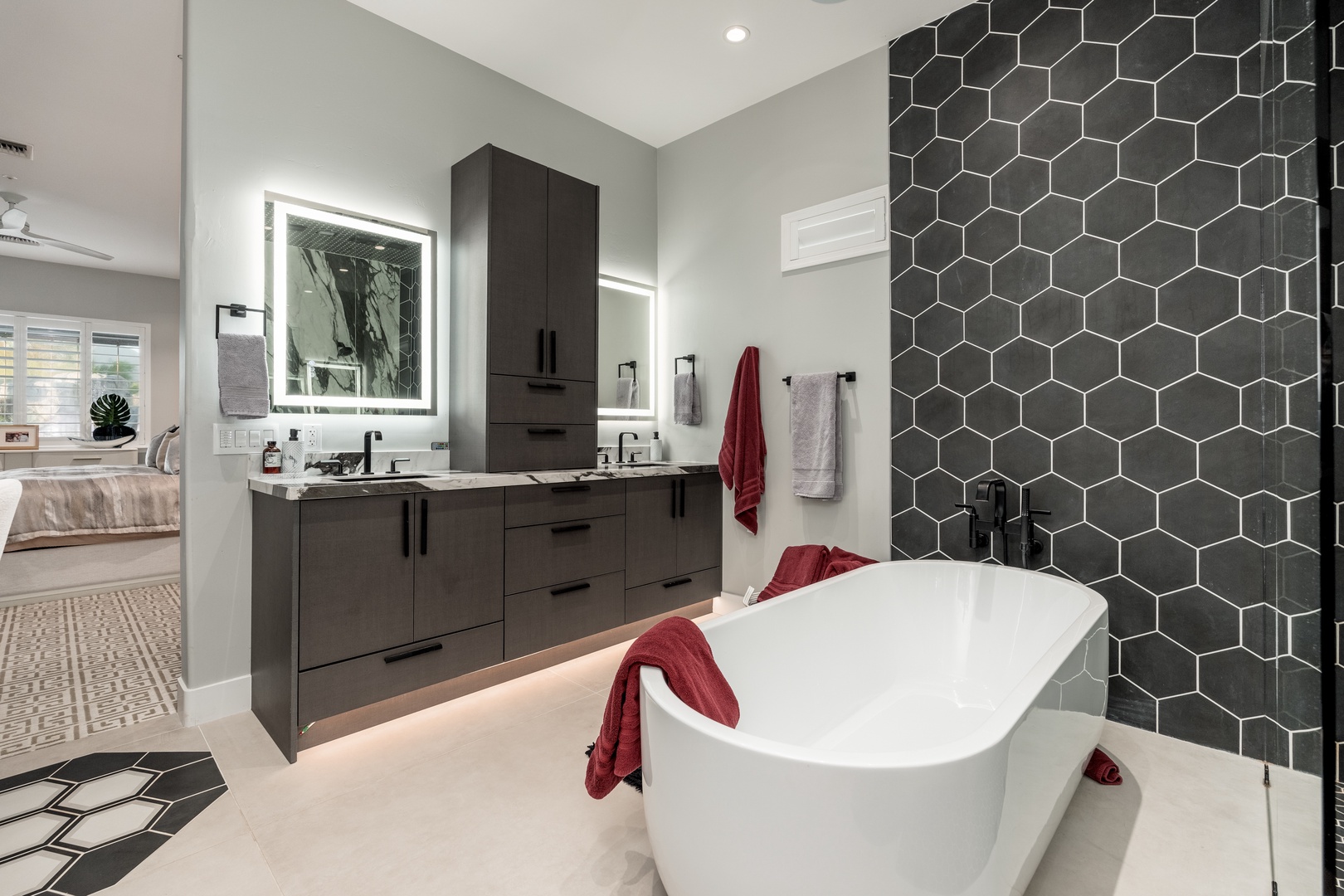 Soak away your cares in this stunning freestanding tub, set against sleek hexagonal tile. Your spa-like retreat features modern double vanities and soft lighting for ultimate relaxation.