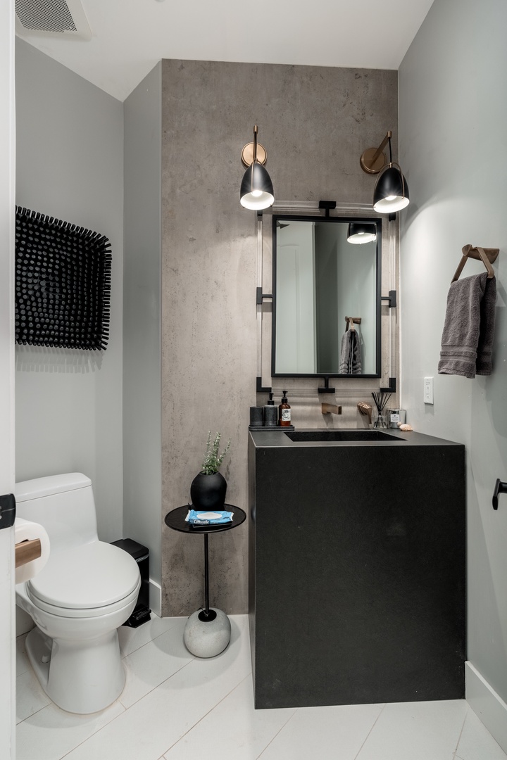 Your private modern bathroom features sleek black fixtures, warm lighting, and thoughtful design touches like fresh towels and curated décor—a stylish retreat awaits.