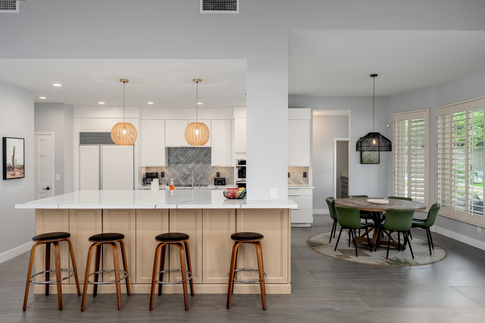 Picture yourself cooking in this bright, modern kitchen with ample counter space, stylish pendant lighting, and an inviting breakfast bar. The adjacent dining nook overlooks lush greenery, creating the perfect setting for morning coffee or evening meals.