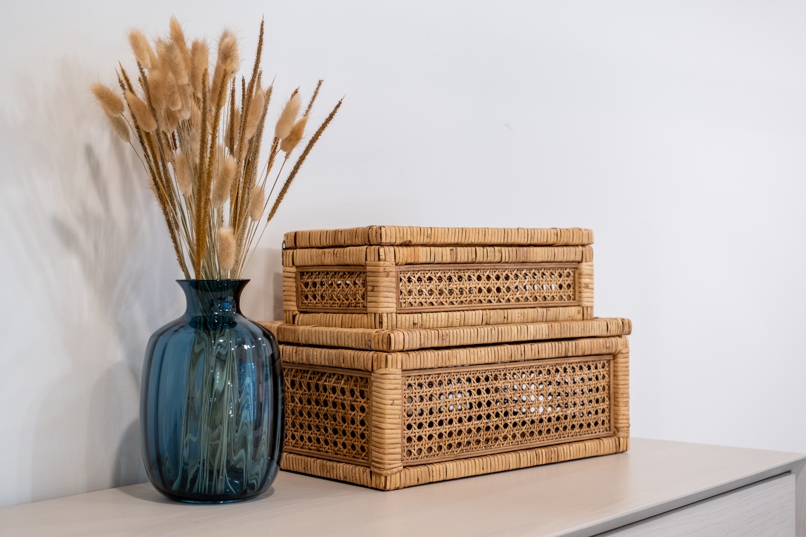 Thoughtful storage solutions meet coastal charm with natural rattan baskets, offering a stylish spot to tuck away your belongings while dried grasses add texture and warmth.