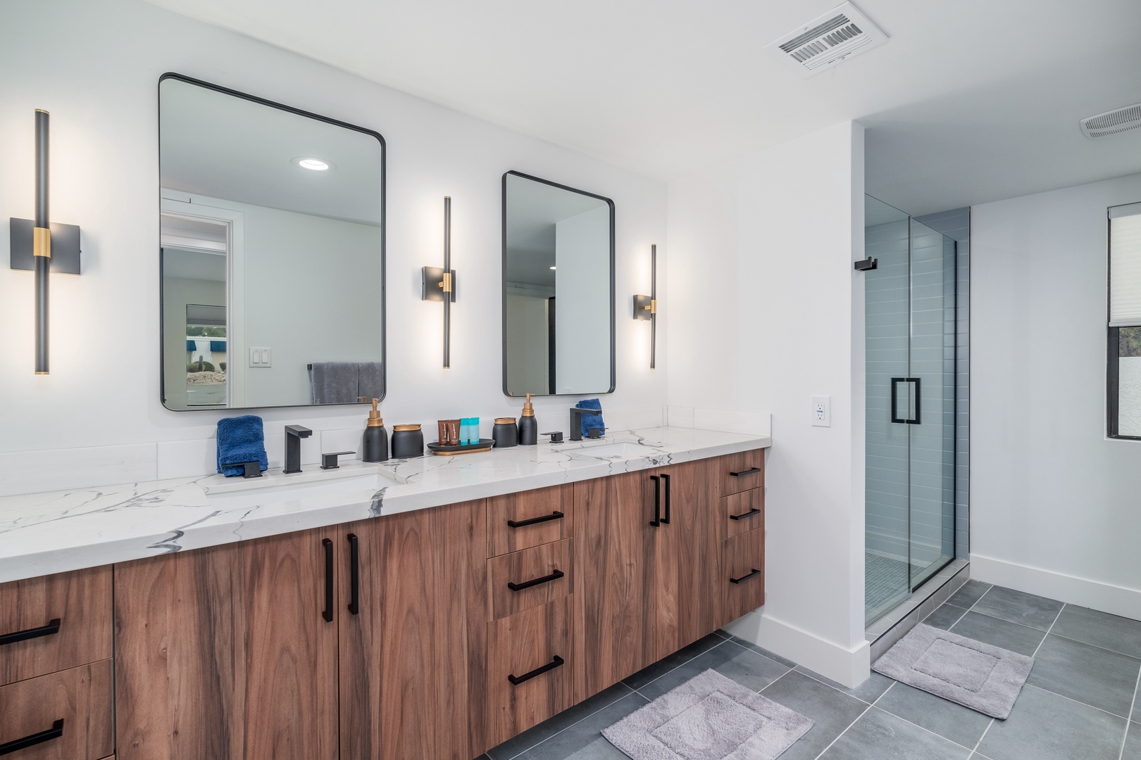 Your spacious dual-vanity bathroom features elegant marble countertops, warm wood cabinetry, modern fixtures, and a luxurious walk-in shower—perfect for refreshing before exploring or unwinding after a day out.