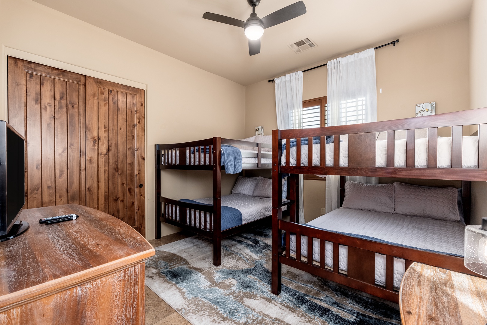 Your cozy bunk room awaits with comfortable bedding, a ceiling fan to keep cool, and entertainment at your fingertips—perfect for kids or groups seeking restful sleep after adventure-filled days.
