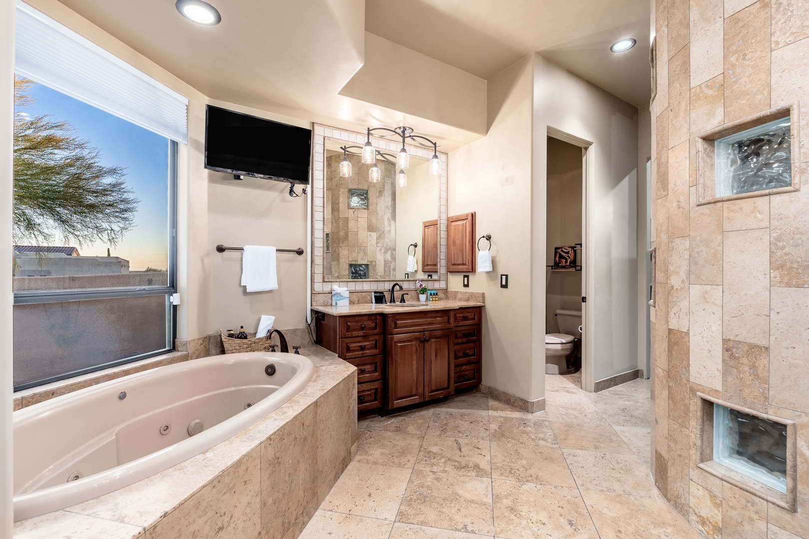 Unwind in your spa-like ensuite featuring a jetted tub, spacious walk-in shower, and serene desert views. Warm wood cabinetry and elegant tile work create a luxurious retreat.