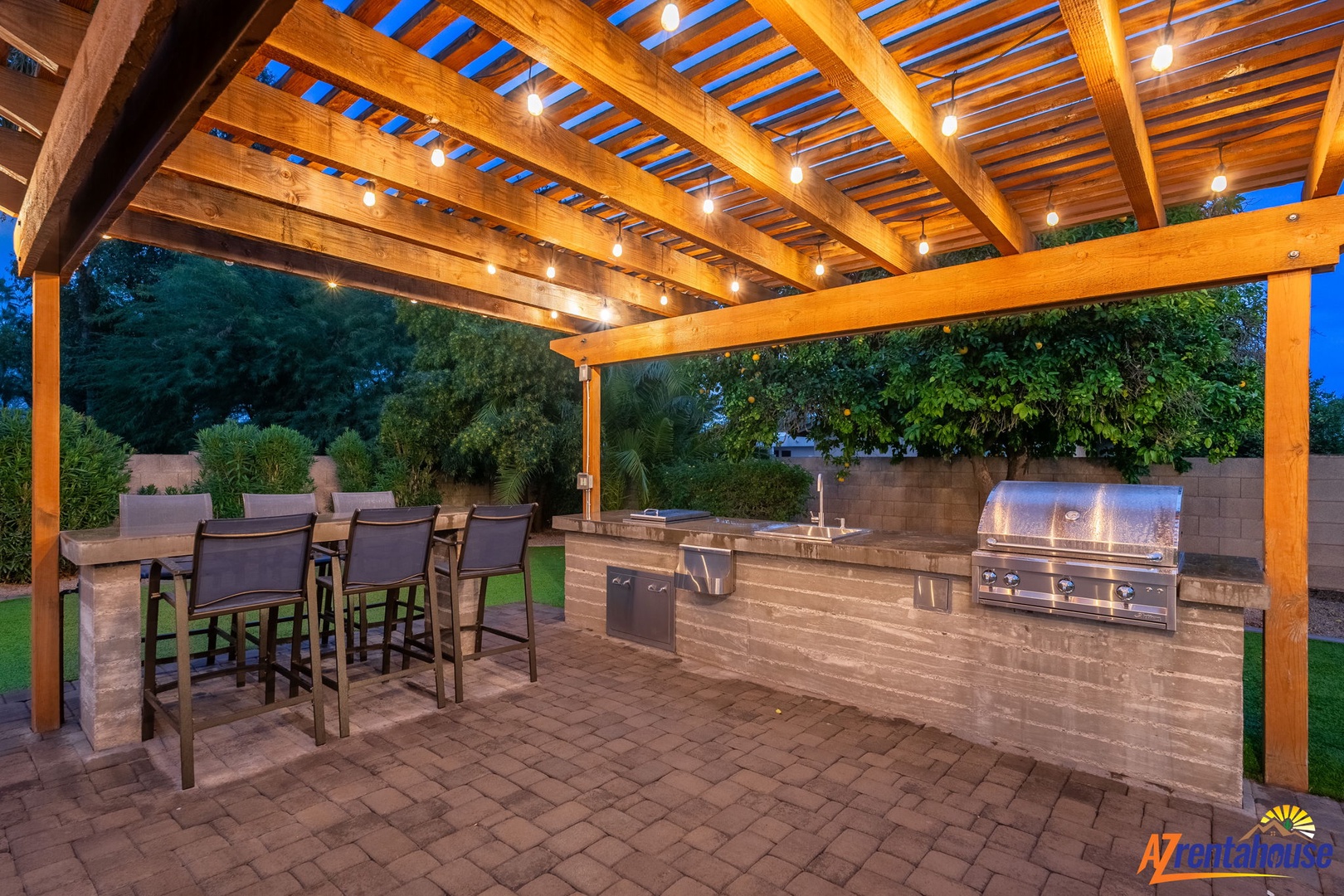 Step into your private outdoor kitchen oasis where string lights create magical ambiance for evening barbecues and al fresco dining.