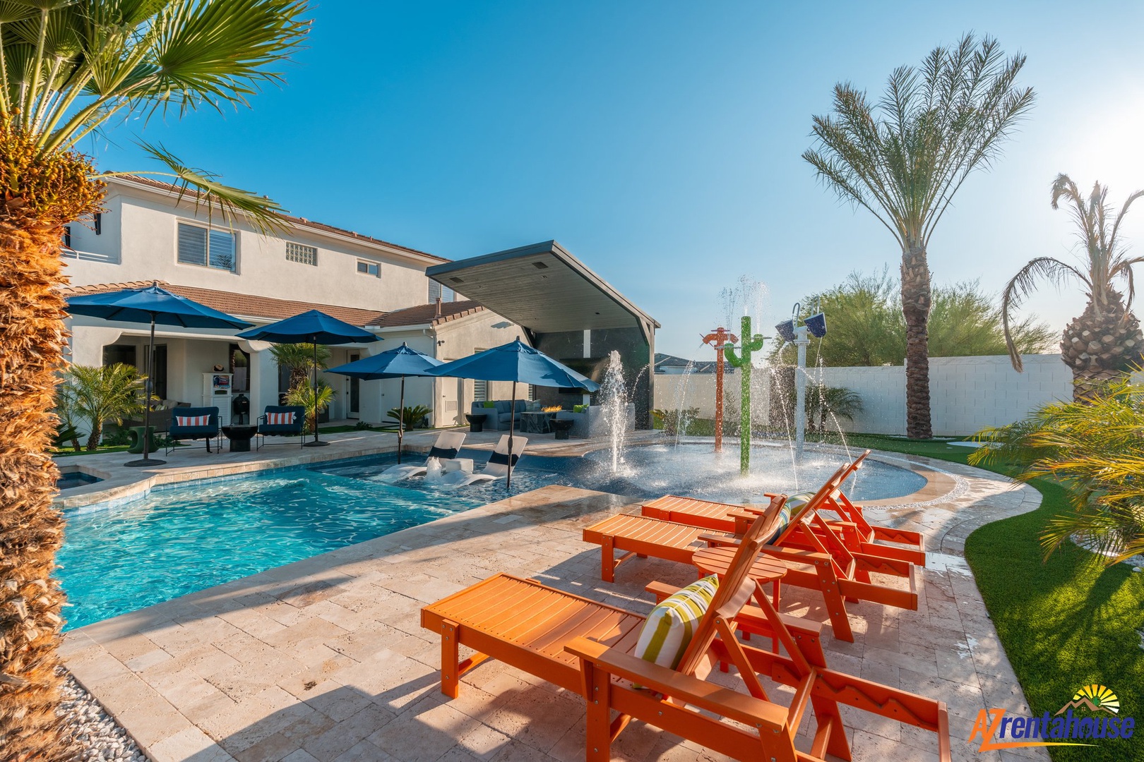 Stunning backyard oasis with sparkling pool, splash fountains, and comfortable lounge chairs under swaying palms.