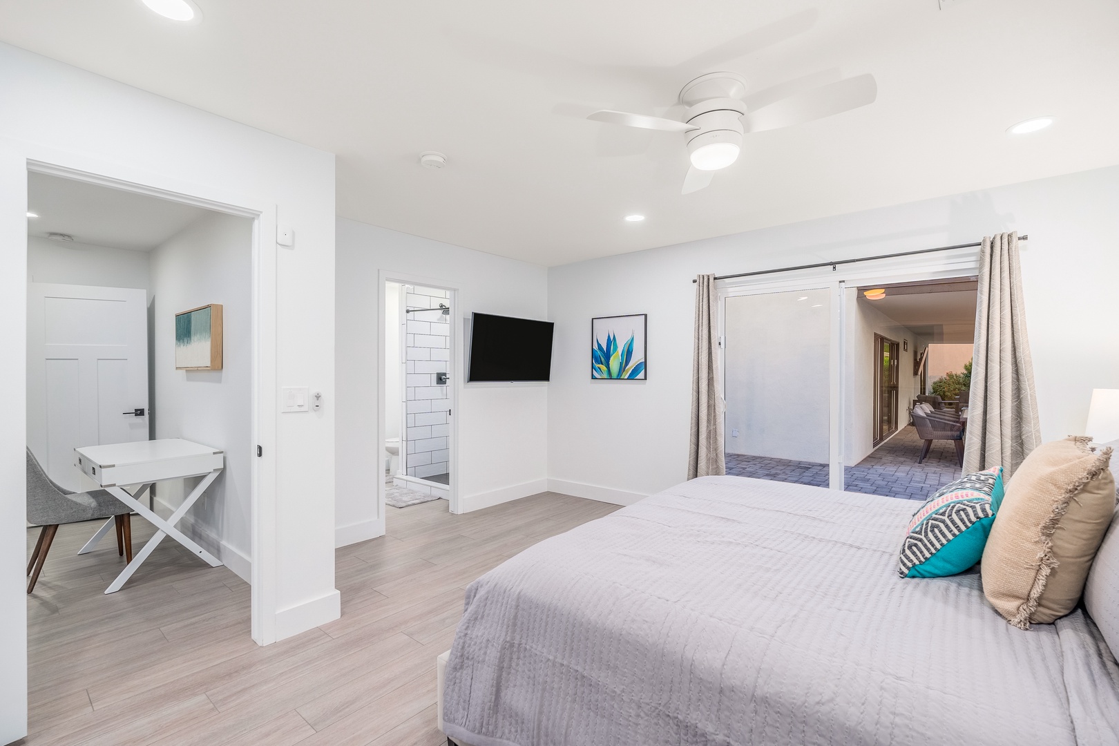 Sink into soft linens in your bright, modern bedroom, where coastal art and soft breezes through open doors invite restful nights and easygoing mornings.