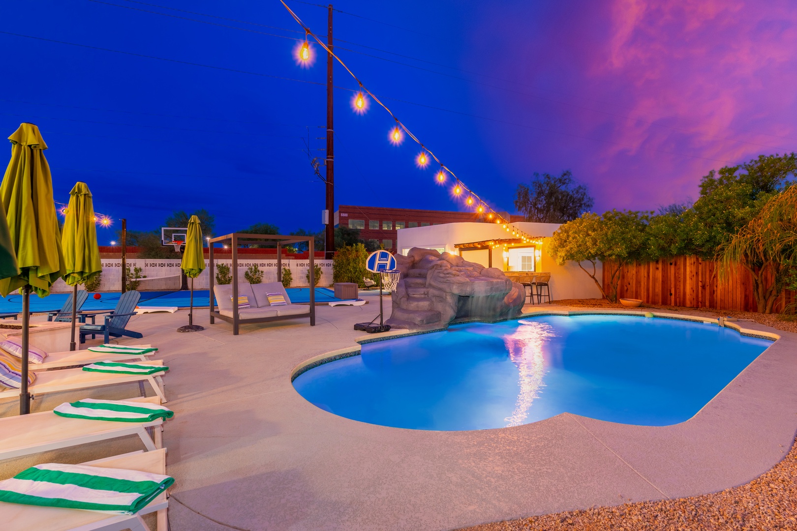 Your private pool glows under string lights at dusk, inviting you to unwind on lounge chairs or dive in from the rock waterslide.