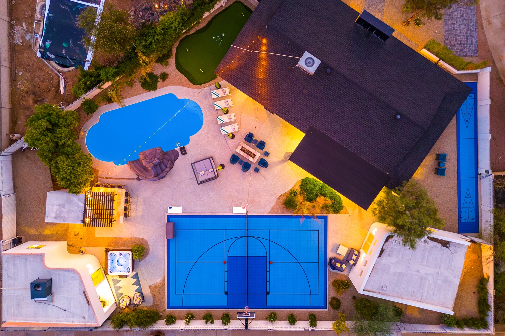 Aerial view of this vacation rental featuring a private pool, full-size basketball court, putting green, and multiple outdoor lounging areas within a spacious property.