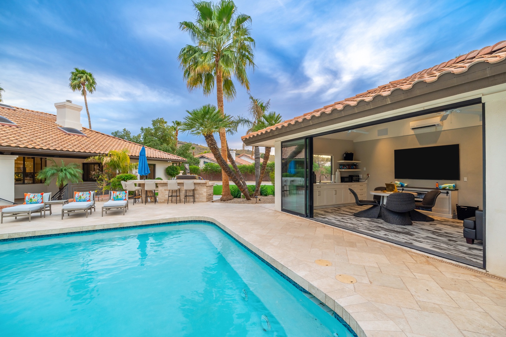 Stunning poolside retreat with palm-lined patio, spacious seating areas, and seamless indoor-outdoor flow where you can relax, entertain, and soak up the desert sunshine in style.