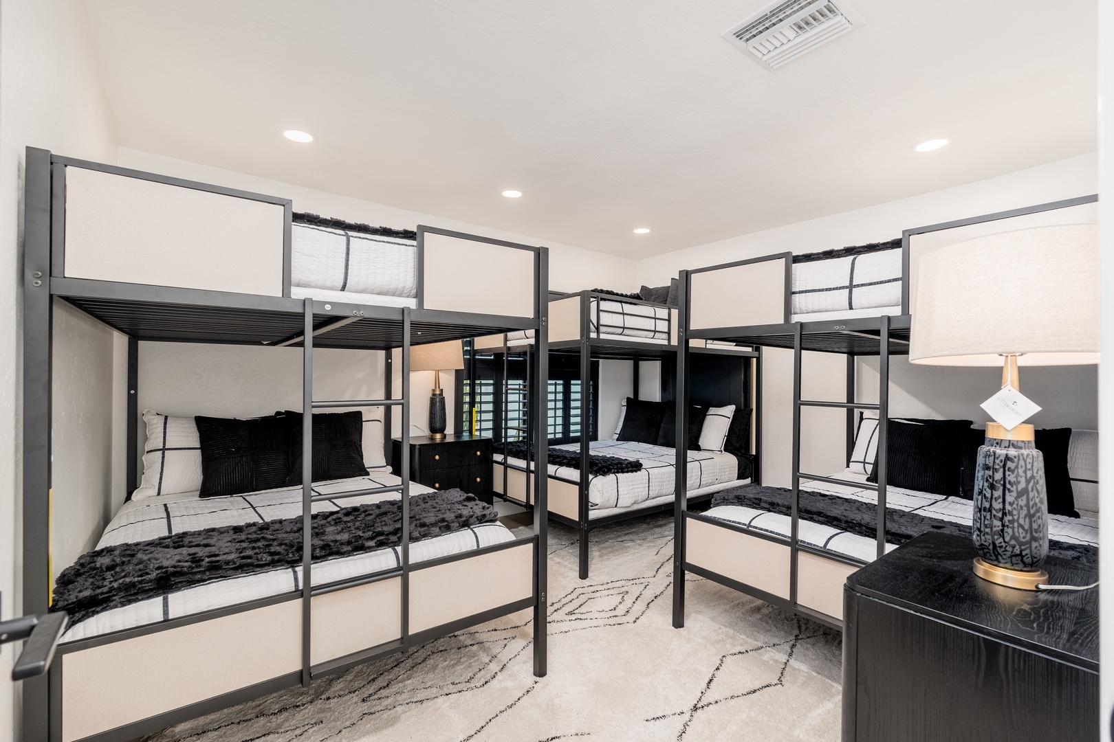 Four sleek bunk beds with plush black throws and crisp white linens create a cozy space for groups or families to rest together.