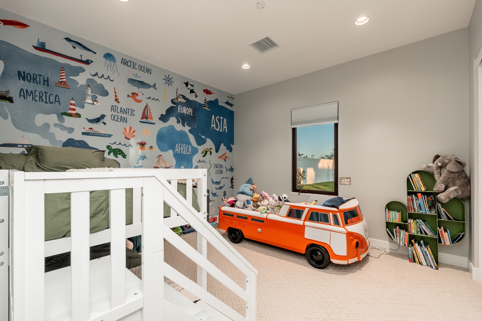 Your little explorer will love this playful bedroom featuring a world map mural, loft bed, and vintage VW bus toy storage. Large windows fill the space with natural light while built-in bookshelves keep adventures organized.