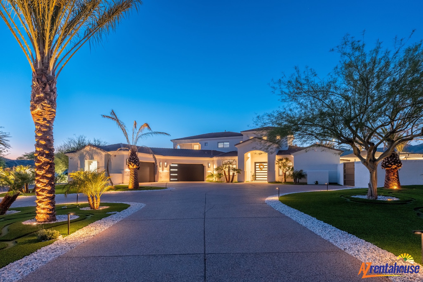 Modern desert luxury villa with elegant palm tree-lined driveway and warm architectural lighting at twilight.