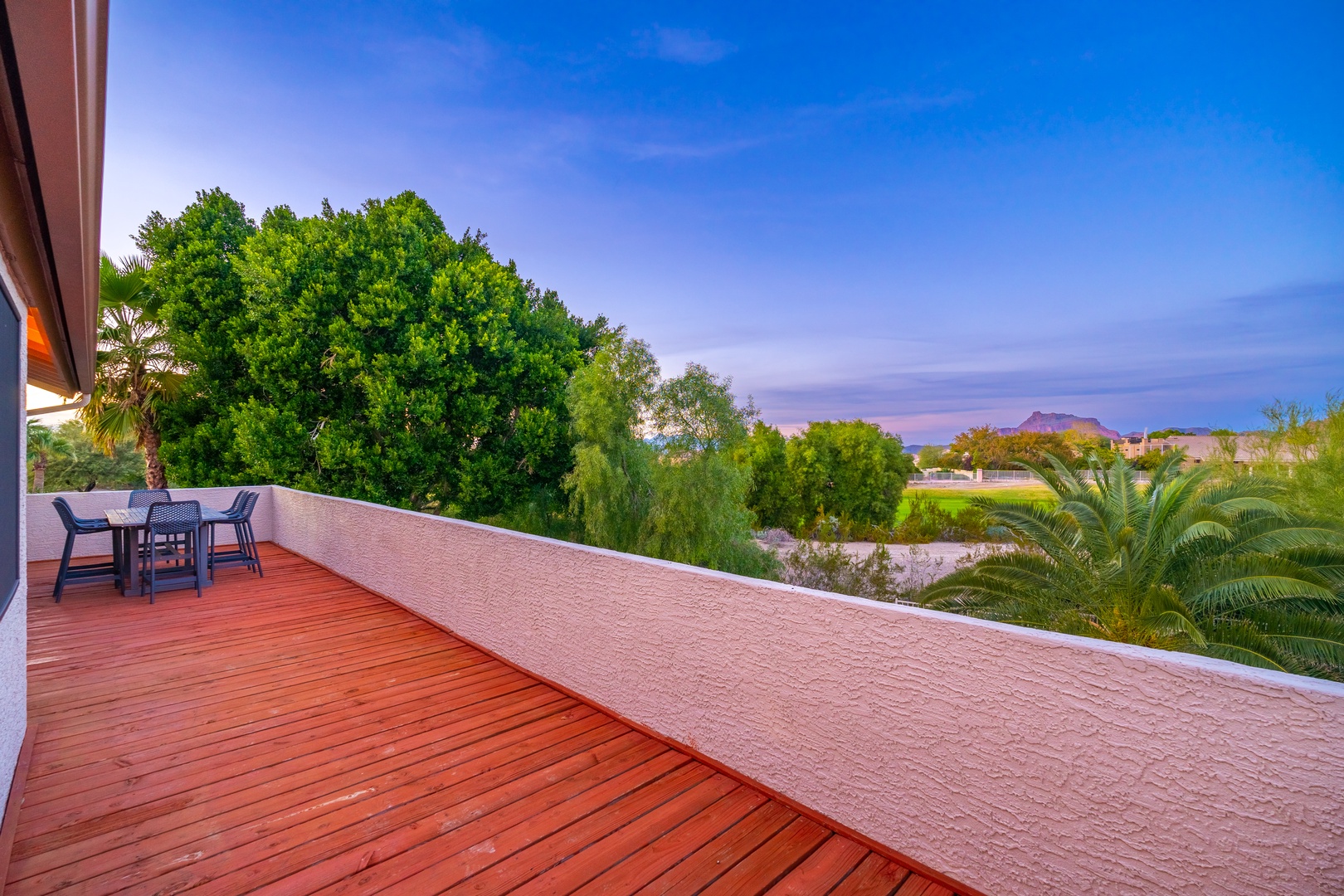 A spacious deck overlooks lush greenery and distant mountains, offering serene views at sunrise or sunset. Perfect for morning coffee or evening relaxation in the fresh air.