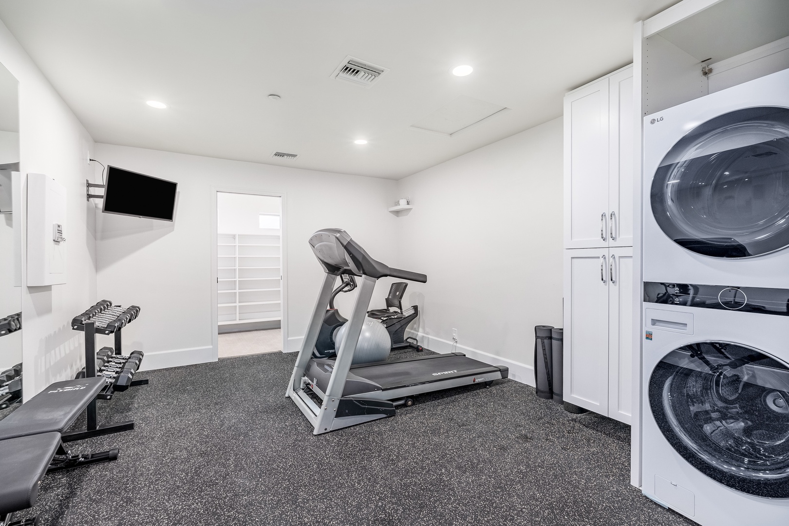 Your private fitness room includes a treadmill, weights, a TV for entertainment, and convenient washer and dryer—everything you need for workouts and laundry during your stay.