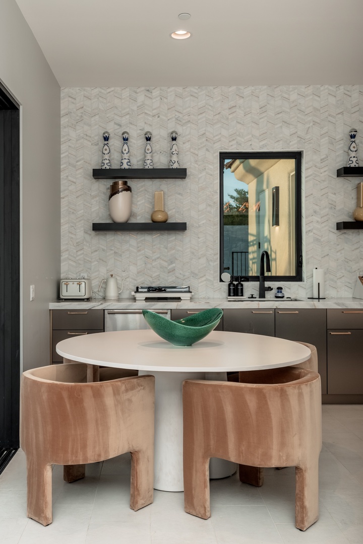 Gather around your modern dining nook with stylish curved seating, elegant herringbone tile backsplash, and sleek countertops perfect for morning coffee or casual meals.