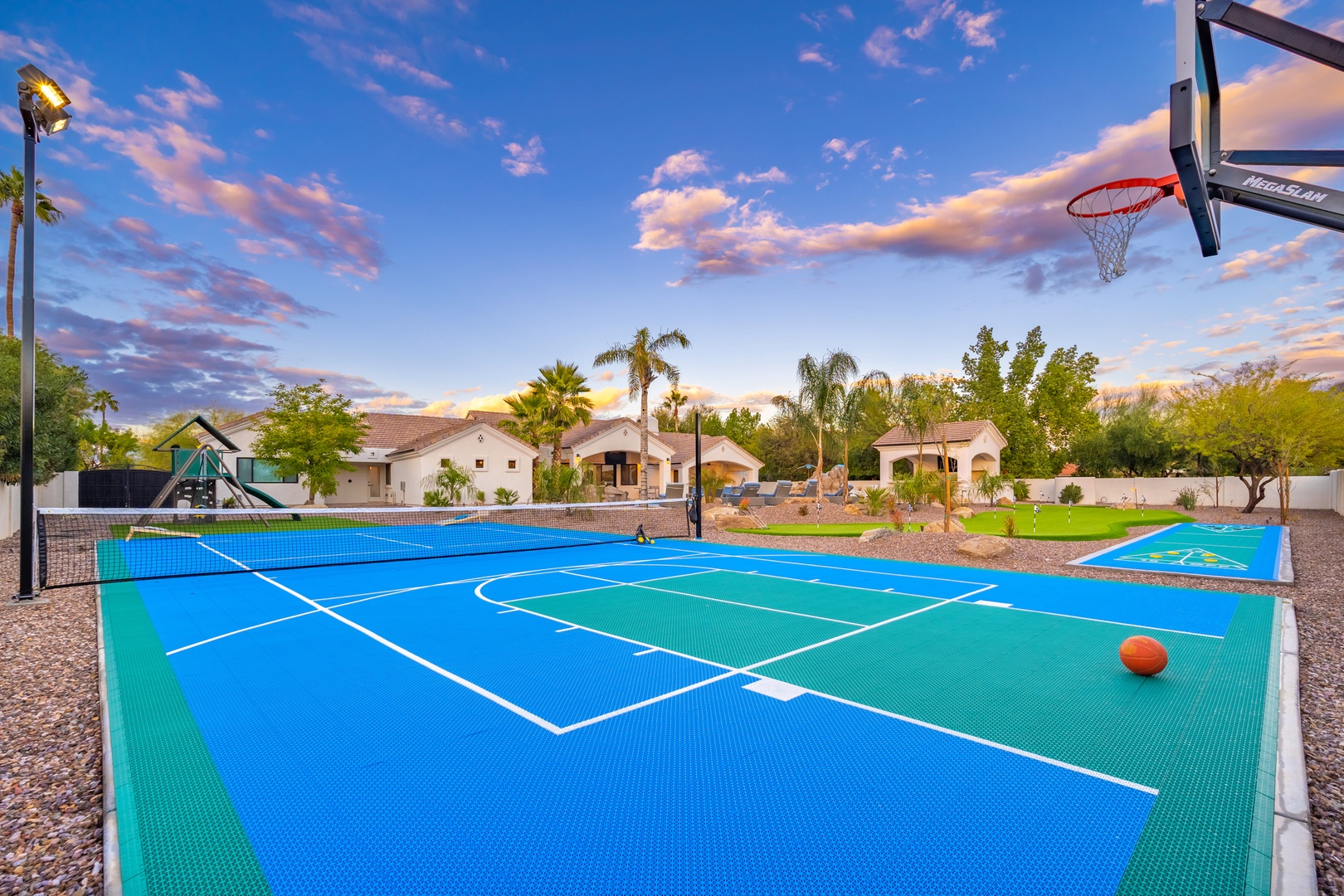 Step onto your private multi-sport court where basketball hoops and tennis lines await friendly competition under stunning desert skies framed by palm trees and mountain views.
