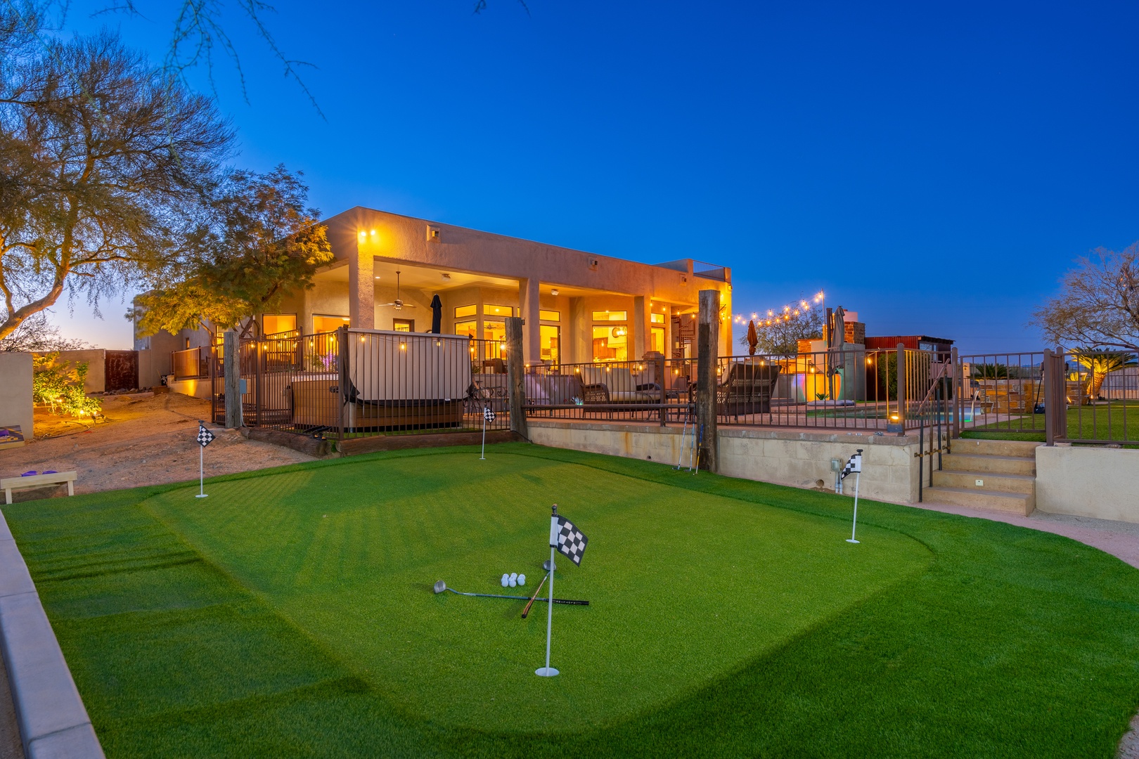 Modern Southwest-style retreat glows warmly at dusk, featuring a private putting green, spacious terraces, and pool area—perfect for entertaining under desert skies.