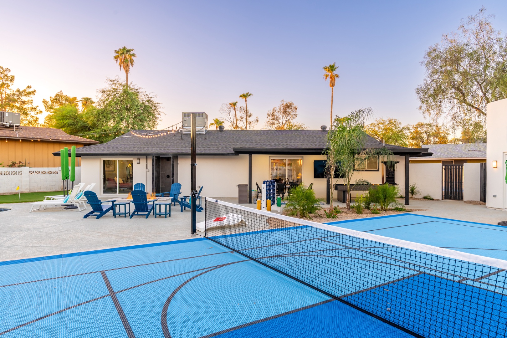 This vacation rental features a private tennis court and spacious outdoor seating area framed by palm trees, perfect for relaxation and recreation during your stay.