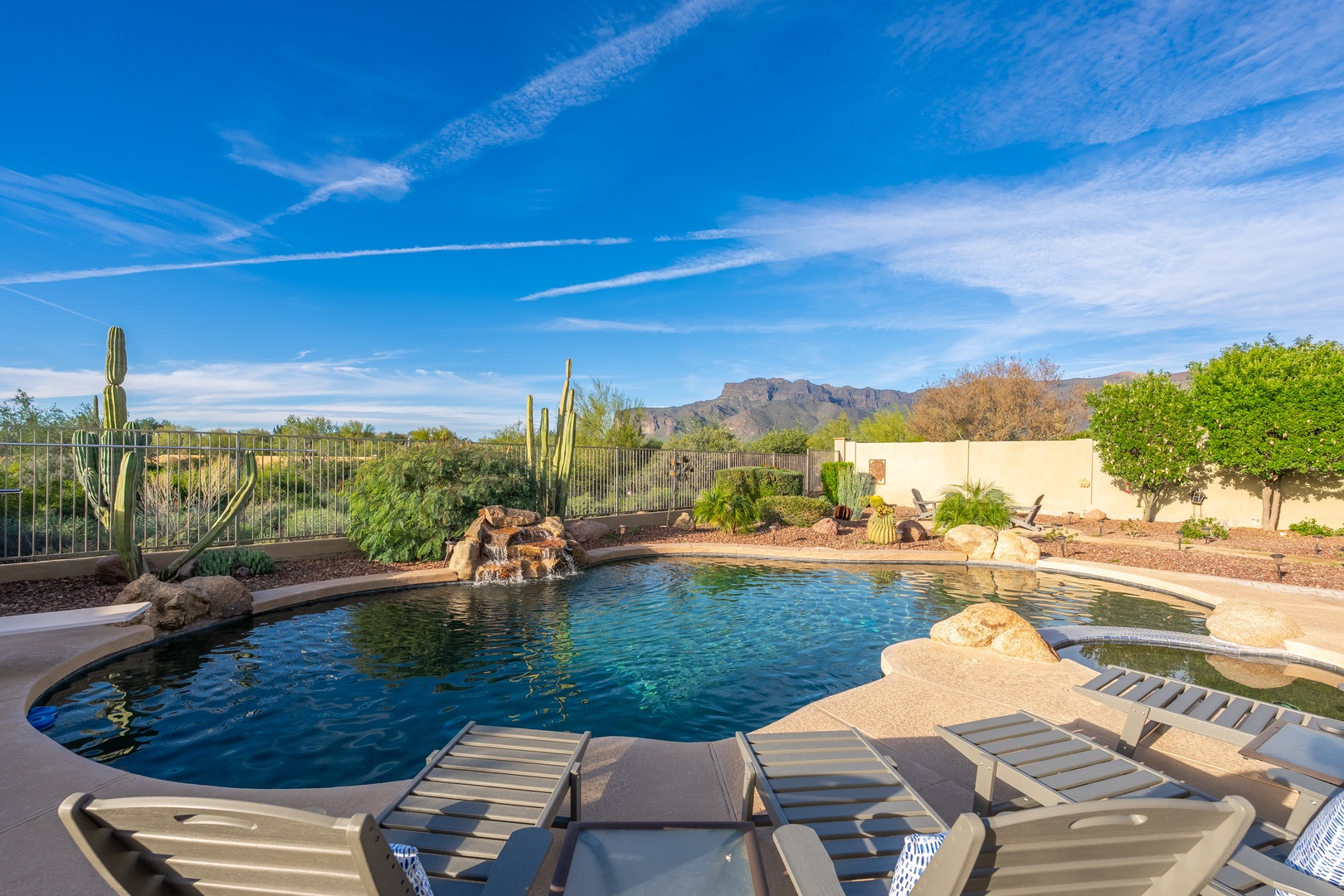 Unwind poolside with mountain views and desert charm. Your private oasis features lounge chairs, natural rock accents, and a serene landscape framed by Sonoran cacti.