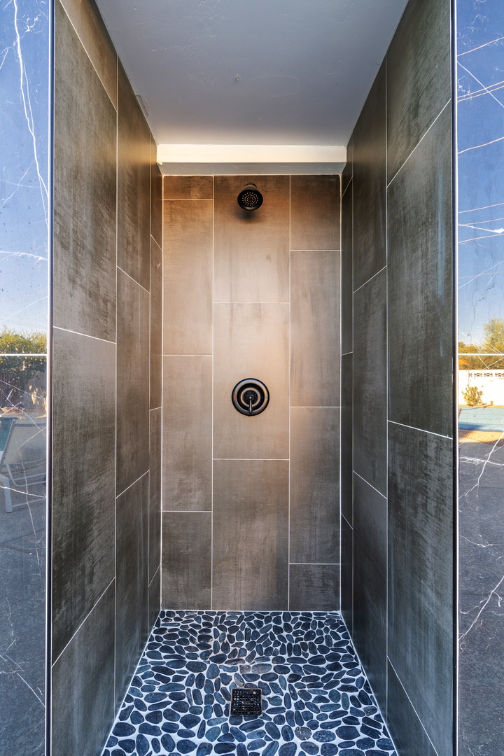A sleek walk-in shower with contemporary tile and smooth stone flooring creates a spa-like sanctuary for refreshing starts and relaxing evenings.