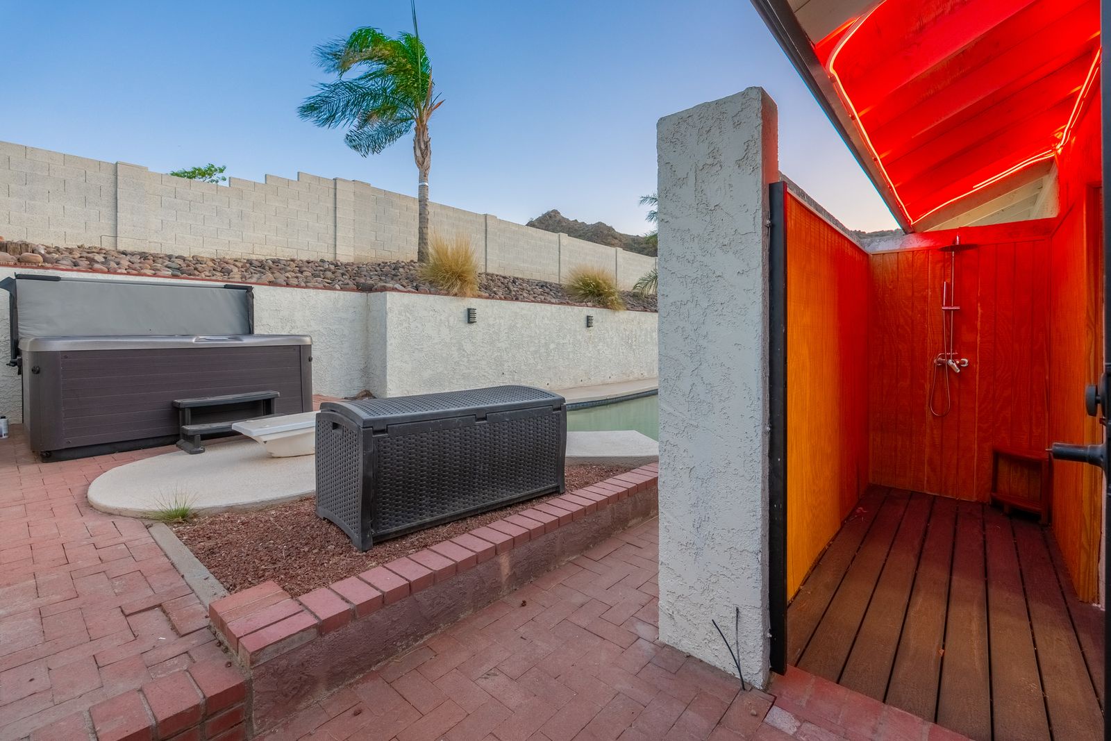 This private outdoor oasis features a hot tub, outdoor shower, and sunny desert landscaping—perfect for relaxing under the palms after a day exploring the area.