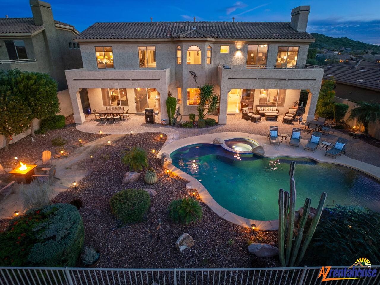 Stunning luxury villa featuring pristine pool, spa, and desert landscaping illuminated against twilight sky.