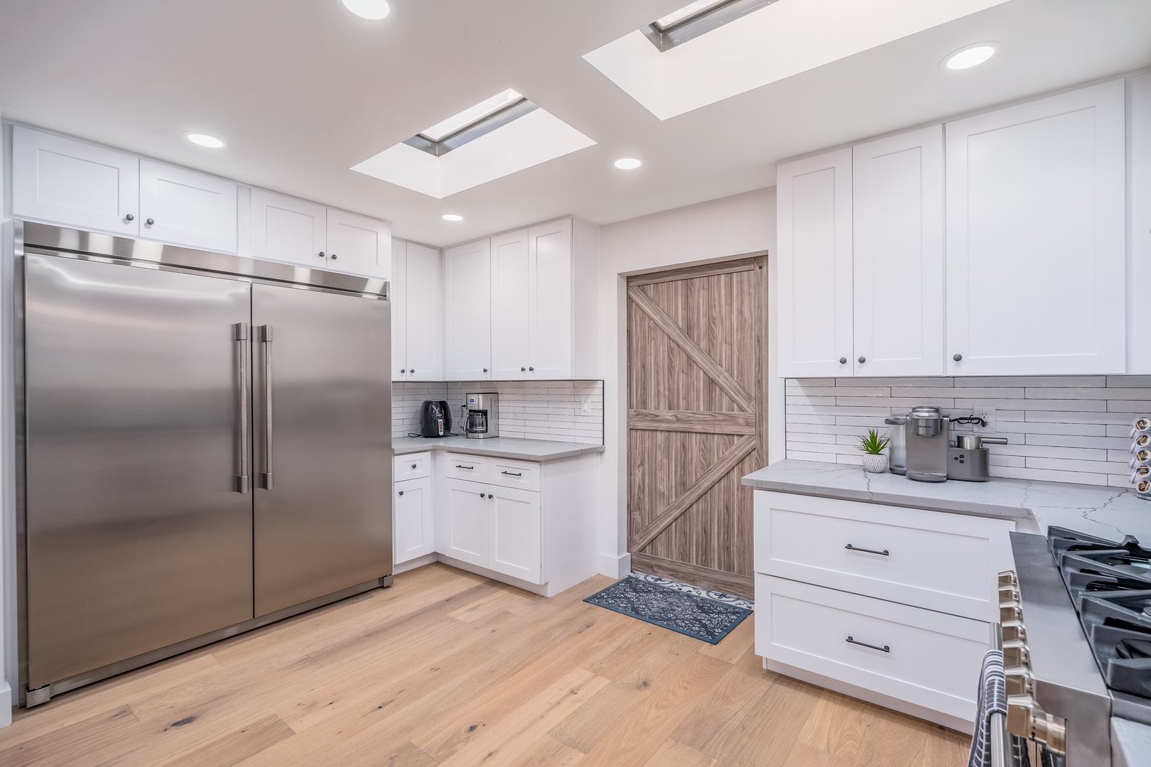 Natural light pours through skylights into your spacious, fully-equipped kitchen—crisp white cabinets, stainless steel appliances, and plenty of counter space invite you to cook and gather comfortably.