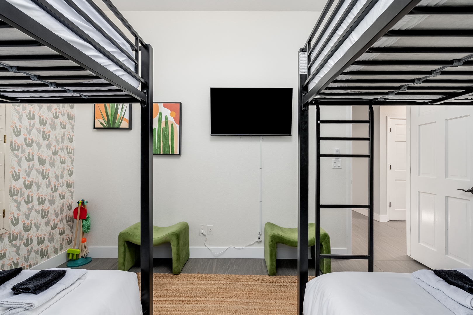 Two bunk beds frame a modern space with cheerful cactus art and matching green chairs—perfect for groups or families traveling together. Unwind and enjoy your favorite shows on the wall-mounted TV.