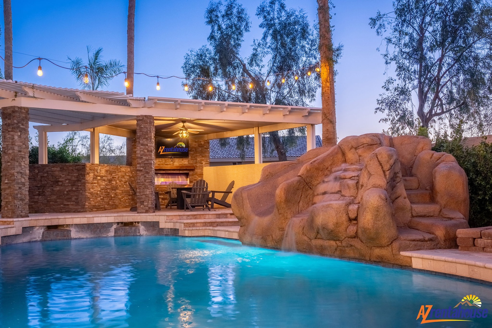 This private oasis features a stunning pool with a cascading rock waterfall and a covered lounge area perfect for evening relaxation under the desert sky.