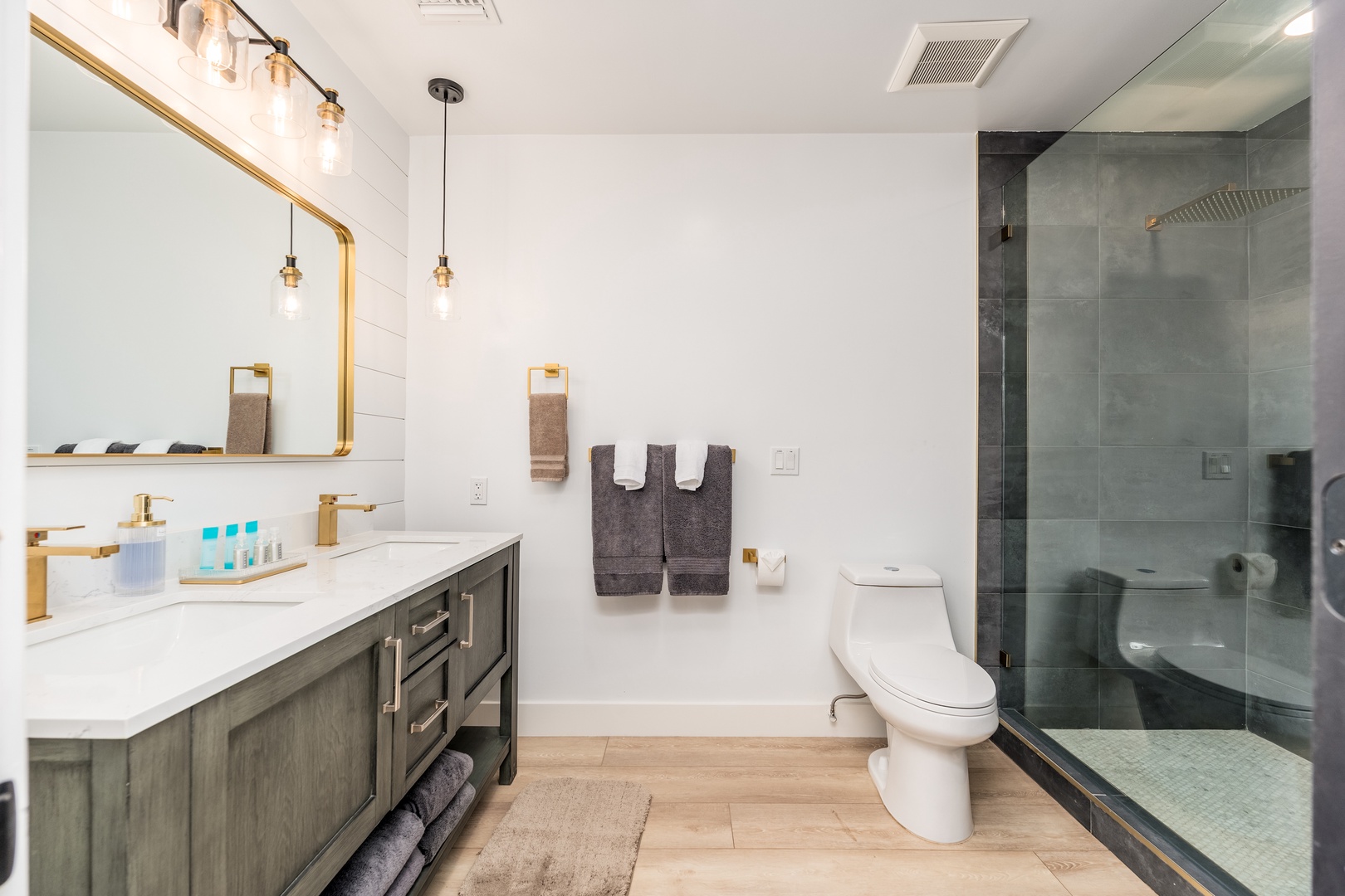 Step into your beautifully appointed bathroom with modern gold fixtures, a spacious walk-in shower, and fresh towels awaiting your arrival—your private retreat for unwinding.
