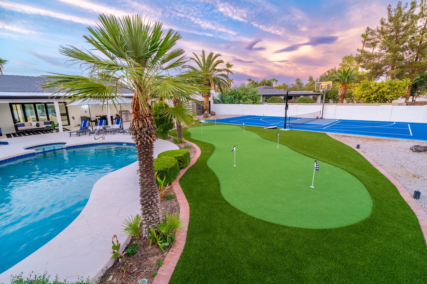 Enjoy your own backyard oasis with a sparkling pool, putting green, and full basketball court—perfect for friendly competition and relaxing under swaying palms.