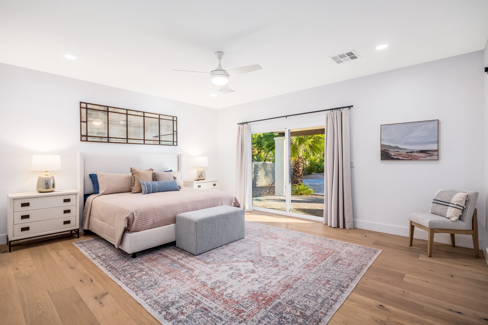 Your serene bedroom opens to a private outdoor oasis through bright glass doors, revealing sparkling pool views and tropical palms. Drift off in coastal comfort.