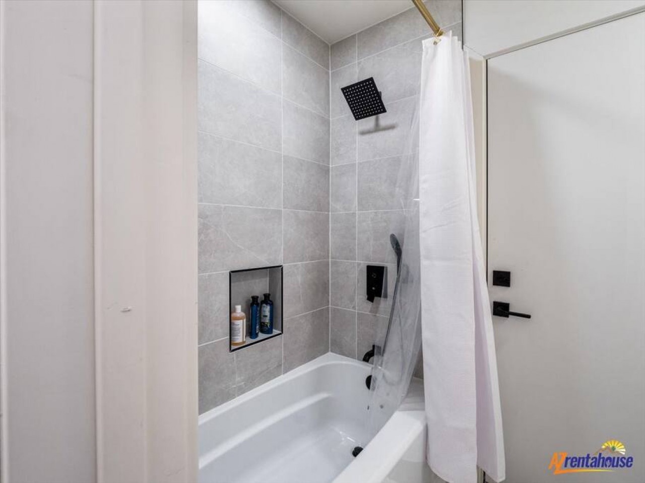 Unwind in your modern bathroom featuring a sleek tub-shower combo with rainfall showerhead and built-in niche for toiletries.