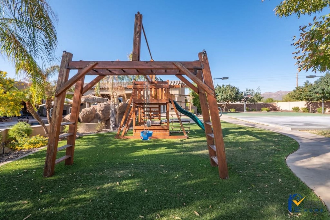 Your little ones can swing high and slide down under sunny skies on this impressive wooden playground set surrounded by lush green grass.