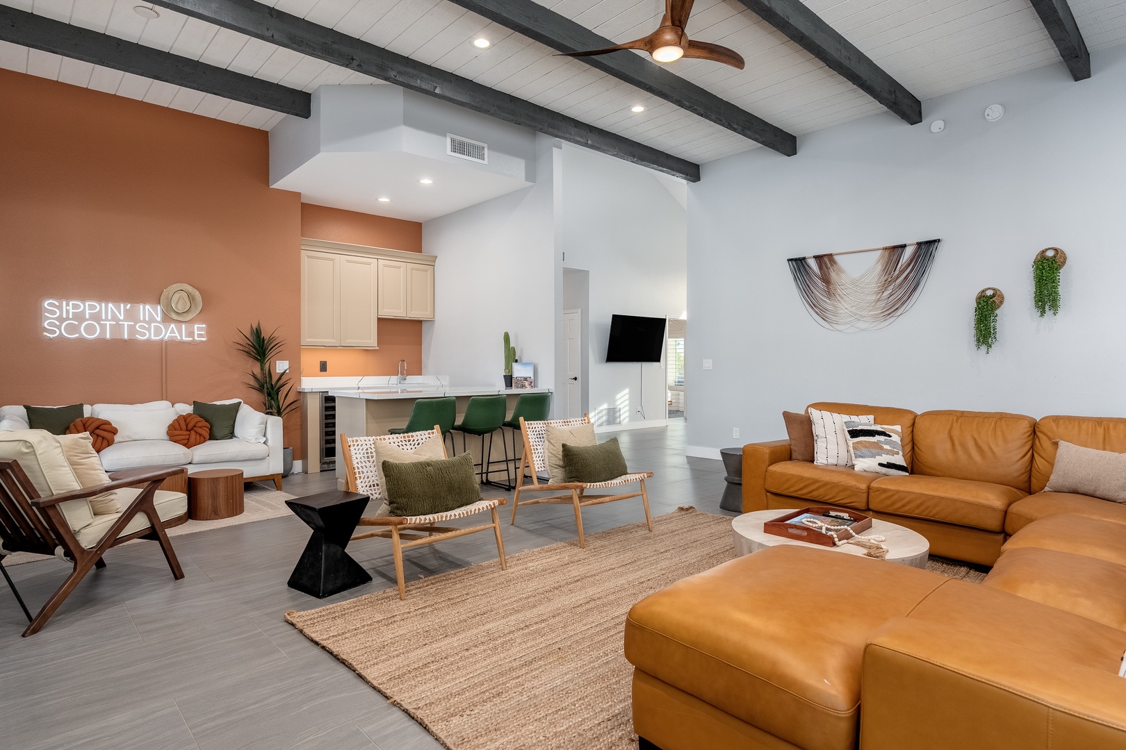 Unwind in this stunning open-concept living space featuring vaulted ceilings with exposed beams, plush seating for your group, and a stylish bar area perfect for cocktails and conversation.