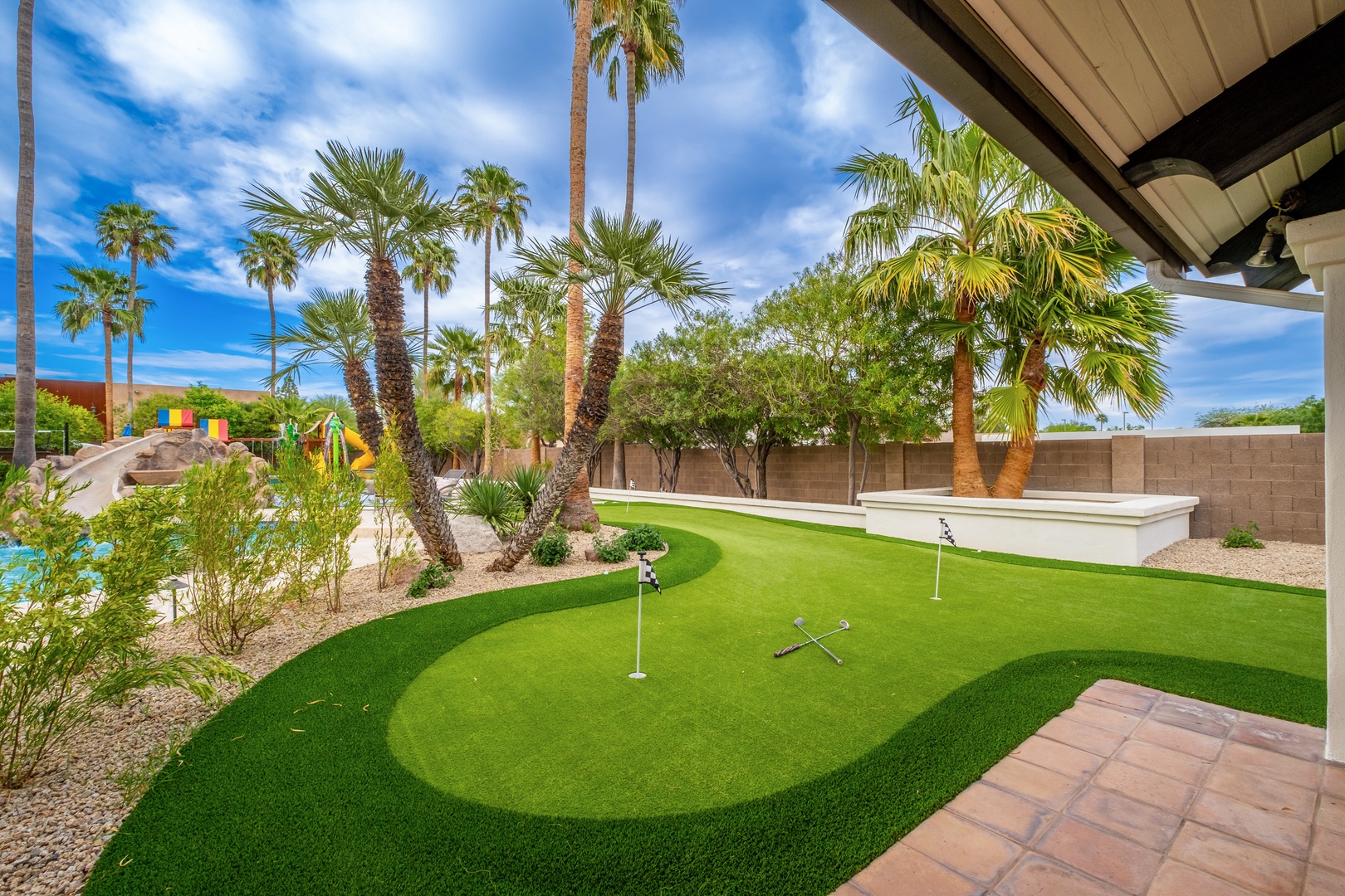 A private putting green surrounded by palm trees and desert landscaping—your own backyard oasis for perfecting your short game under sunny skies.