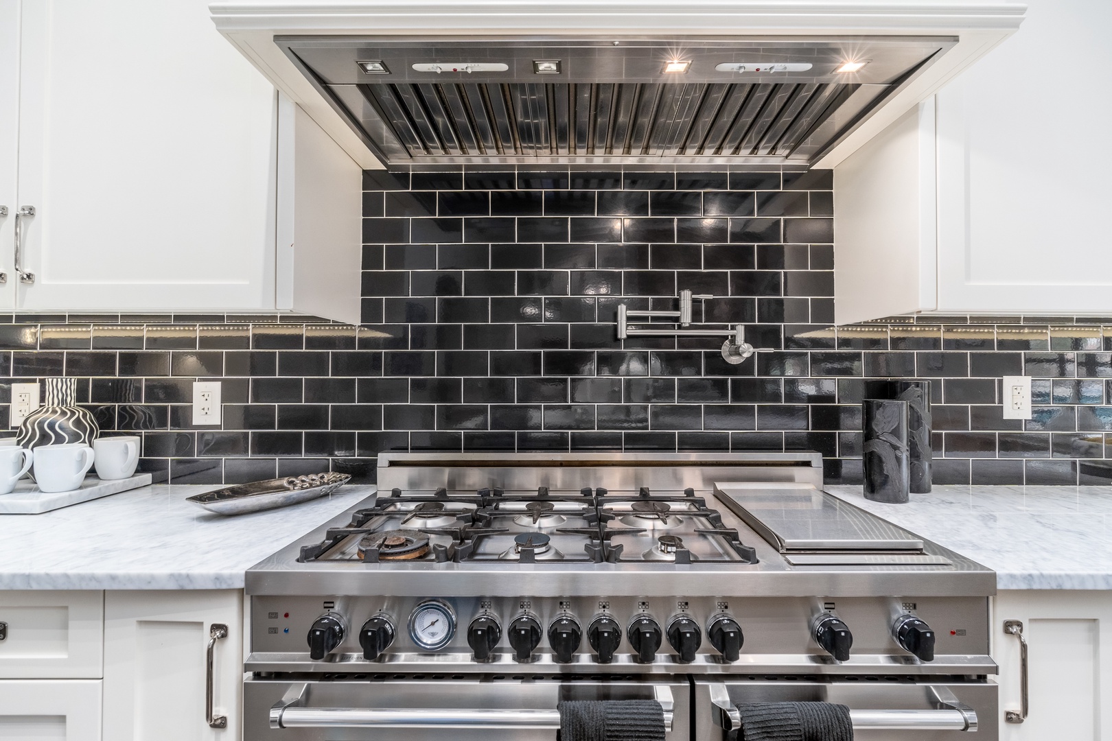 Your private kitchen features a professional-grade gas range with griddle, sleek marble countertops, elegant subway-tile backsplash, and powerful ventilation—perfect for preparing memorable vacation meals.