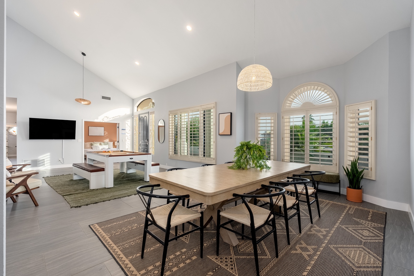 Light-filled open living space blends dining and lounge areas, with high ceilings, elegant shuttered windows, and stylish modern furnishings creating a warm, welcoming retreat.