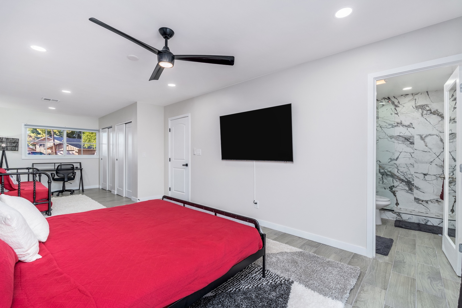 Relax in your bright, modern bedroom with a plush bed, ceiling fan, wall-mounted TV, and a stunning marble-accented ensuite bathroom just steps away.