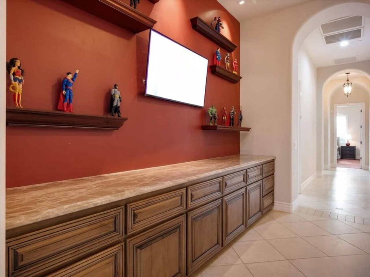 Your entertainment center features a mounted screen and custom cabinetry, with character collectibles adding a playful touch to movie nights and downtime together.