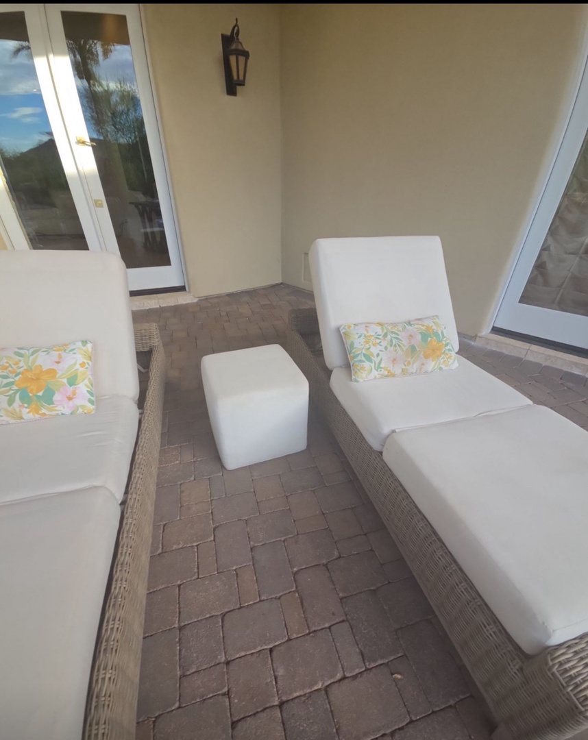 Unwind on your private covered patio with plush lounge seating and cheerful floral accents, perfect for morning coffee or evening relaxation.