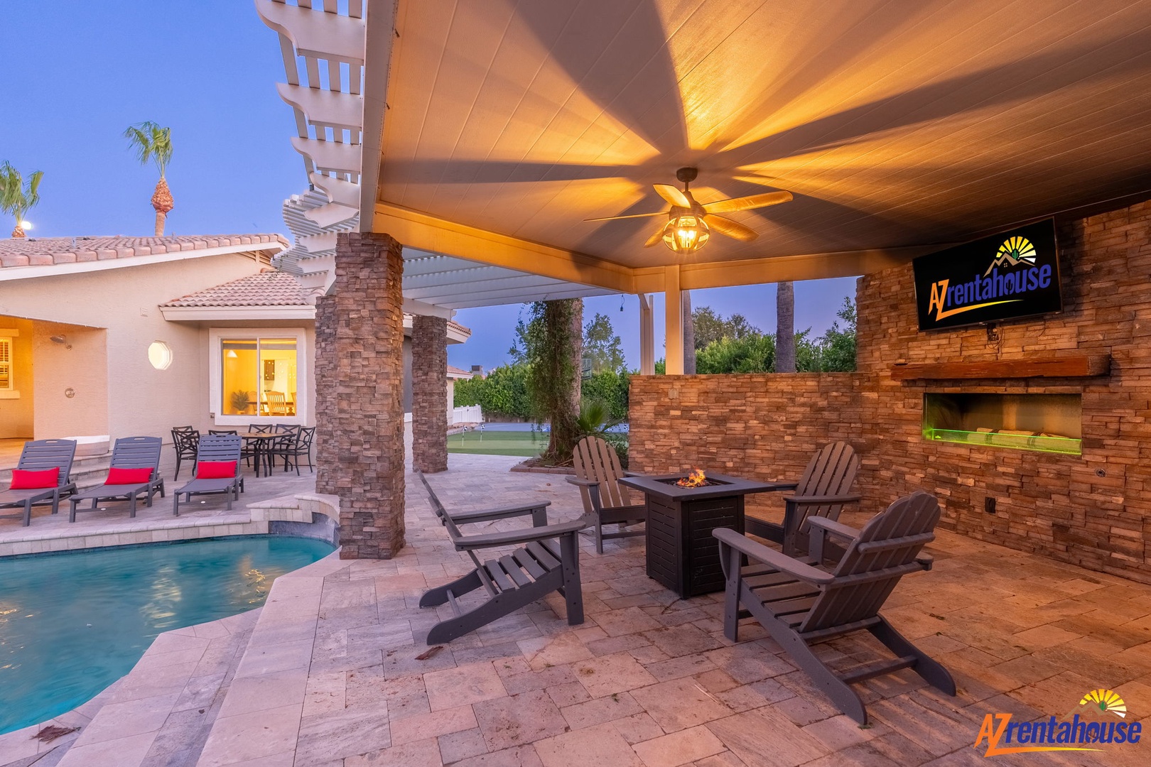 The covered patio creates an inviting retreat for evening gatherings by the pool, complete with Adirondack chairs around a cozy fire pit and an outdoor TV for memorable nights under Arizona skies.