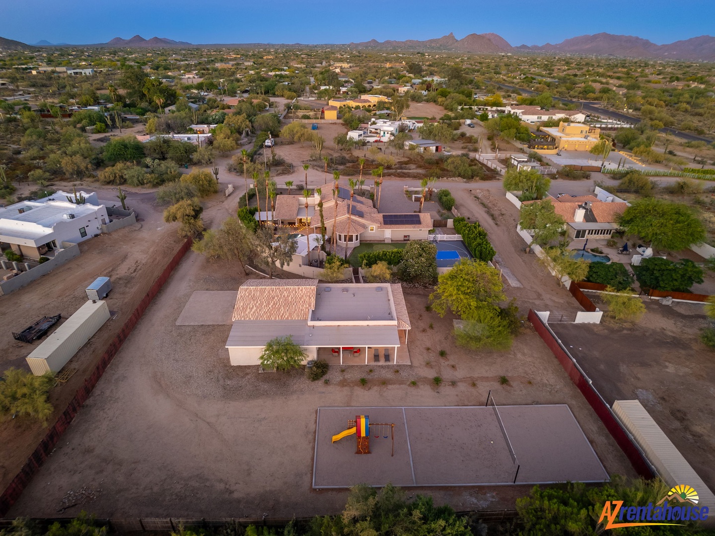 Aerial view of a spacious desert property with mountain vistas, residential neighborhood setting, and on-site playground area in a tranquil southwestern landscape.